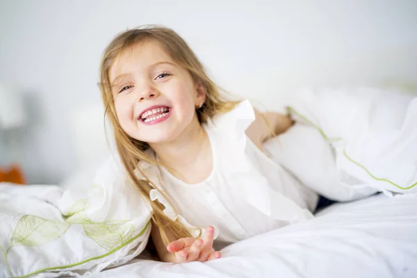 Очаровательная маленькая девочка проснулась в своей постели — стоковое фото