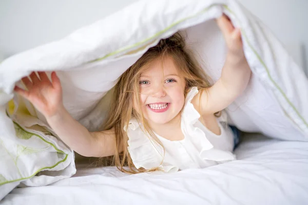 Очаровательная маленькая девочка проснулась в своей постели — стоковое фото