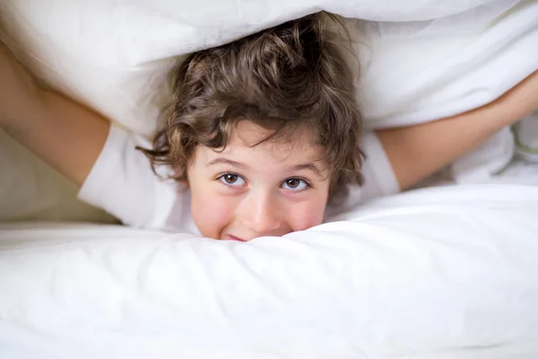 Αξιολάτρευτο μικρό αγόρι στο λευκό t-shit ξαπλωμένη στο κρεβάτι — Φωτογραφία Αρχείου