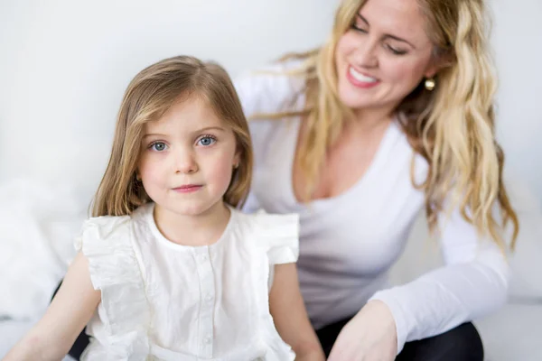 Petite fille mignonne et sa mère allongée sur un lit — Photo