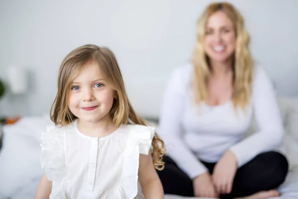 Petite fille mignonne et sa mère allongée sur un lit — Photo