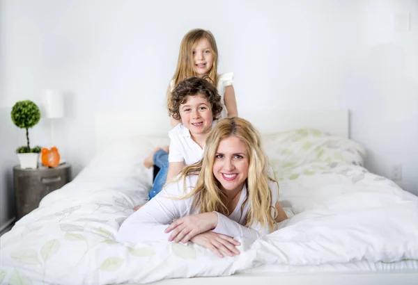 Portrait d'une mère heureuse et de ses enfants couchés sur un lit — Photo