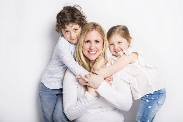 Mãe, seu filho e filha na frente de fundo branco — Fotografia de Stock