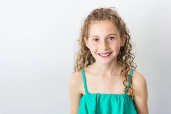 Ritratto di ragazza felice, sorridente, sicura di sé, di 9 anni, con i capelli ricci, isolata sul grigio — Foto Stock