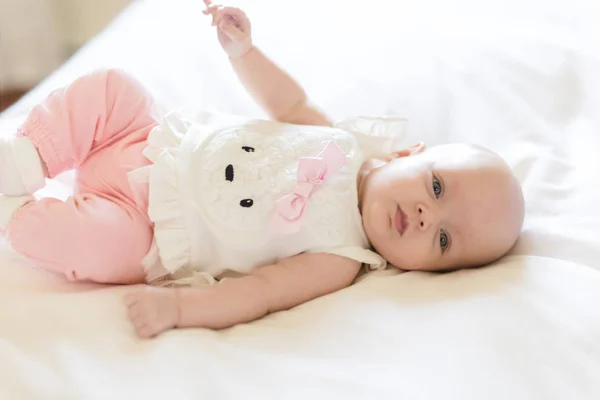 Baby flicka lägger på en vit säng — Stockfoto