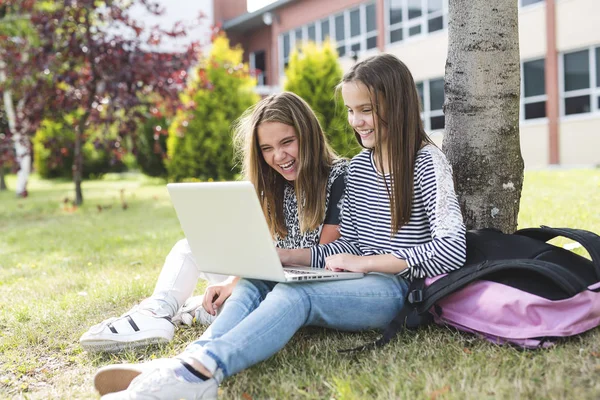 Deux étudiantes souriantes sont assises sur l'herbe . — Photo