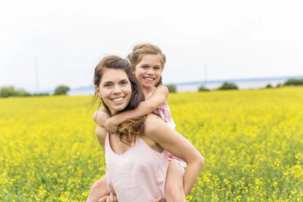 Glückliche Familie Mutter und Kind Tochter Umarmung auf gelben Blumen in der Natur im Sommer — Stockfoto
