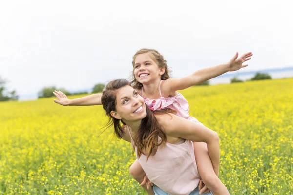 Glückliche Familie Mutter und Kind Tochter Umarmung auf gelben Blumen in der Natur im Sommer — Stockfoto