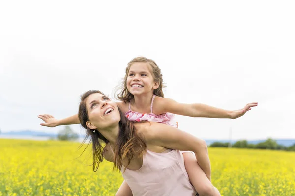 Glückliche Familie Mutter und Kind Tochter Umarmung auf gelben Blumen in der Natur im Sommer — Stockfoto