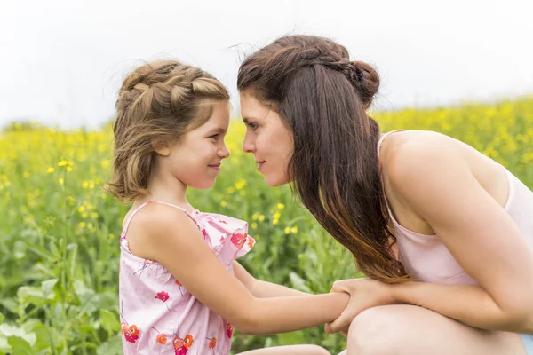 Glückliche Familie Mutter und Kind Tochter Umarmung auf gelben Blumen in der Natur im Sommer — Stockfoto