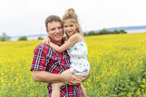 Happy family father and child daughter on yellow flowers on nature in summer — Stock Photo, Image