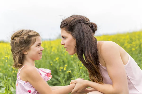 Glückliche Familie Mutter und Kind Tochter Umarmung auf gelben Blumen in der Natur im Sommer — Stockfoto