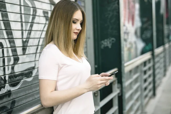 Молодая женщина использует смартфон на открытом воздухе — стоковое фото