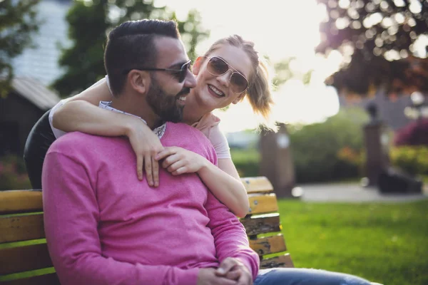 Couple sitting on a bench at the sunset in the city — Stock Photo, Image