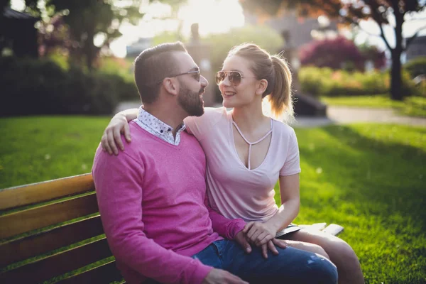 Couple sitting on a bench at the sunset in the city — Stock Photo, Image