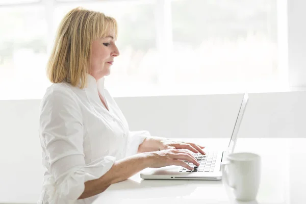 Mature woman using laptop at home — Stock Photo, Image