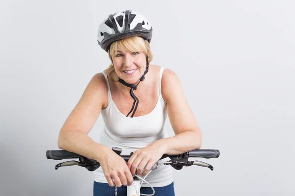 Senior woman on the side of a bike in studio white background — Stock Photo, Image