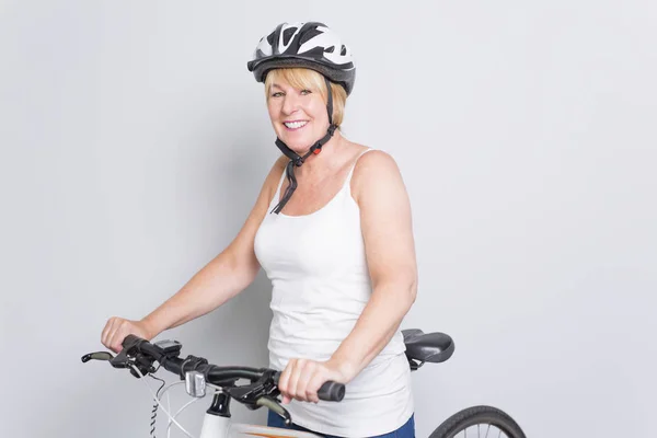 Mujer mayor en el lado de una bicicleta en el estudio fondo blanco —  Fotos de Stock