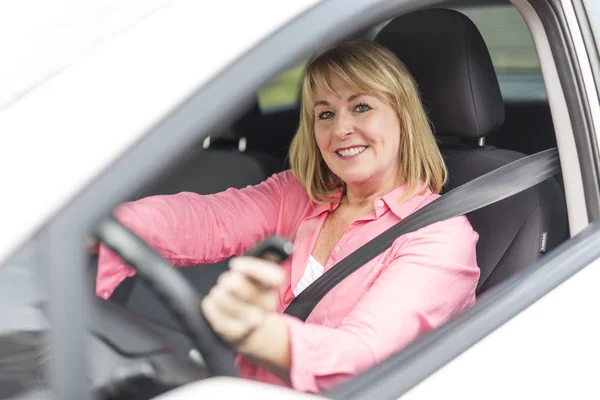 Happy and smiling senior woman in black car — Stock Photo, Image