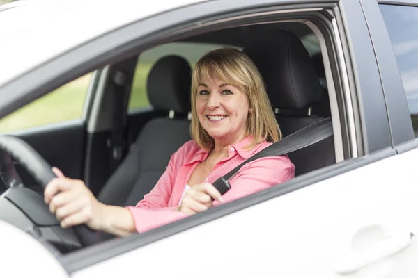 Happy and smiling senior woman in black car — Stock Photo, Image