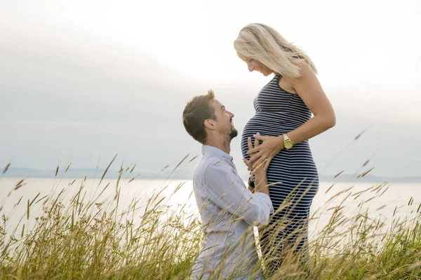 Donna incinta in spiaggia con marito che si diverte — Foto Stock