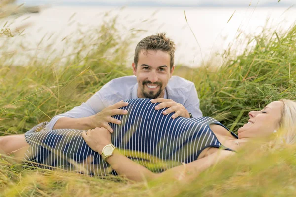 Mujer embarazada en la playa con marido divirtiéndose — Foto de Stock