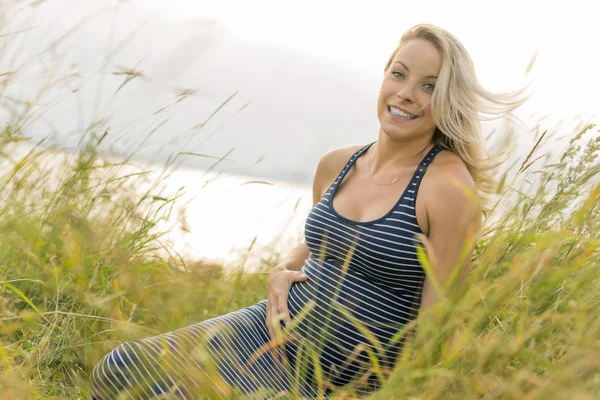 Portret van een jonge mooie blonde zwangere vrouw aan de kant van het strand — Stockfoto