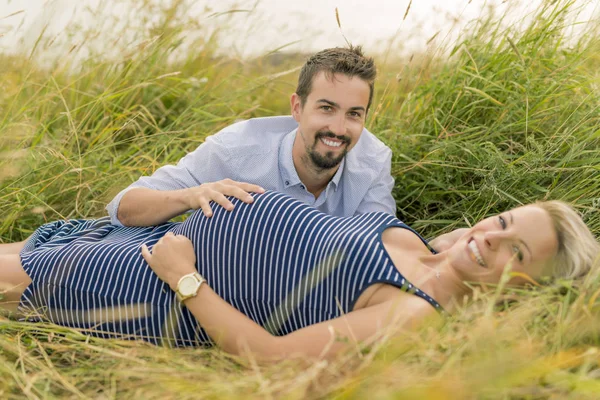 Mulher grávida na praia com o marido se divertindo — Fotografia de Stock