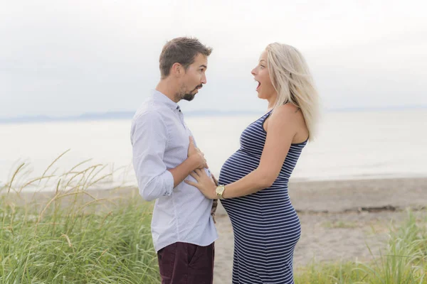 Těhotná žena na pláži s manželem baví — Stock fotografie