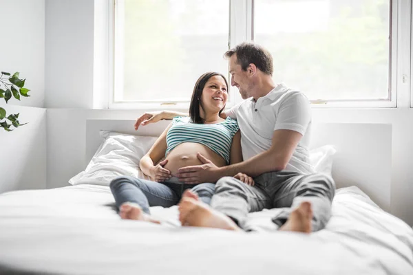 Jeunes parents au lit attendant un petit bébé, Moments romantiques pour couple enceinte — Photo