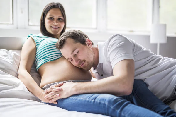 Młodzi rodzice w łóżku spodziewa się małe dziecko, romantyczne chwile w ciąży kilka — Zdjęcie stockowe