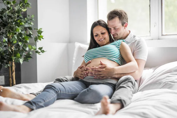 Молодые родители в постели ждут ребенка, романтические моменты для беременной пары — стоковое фото