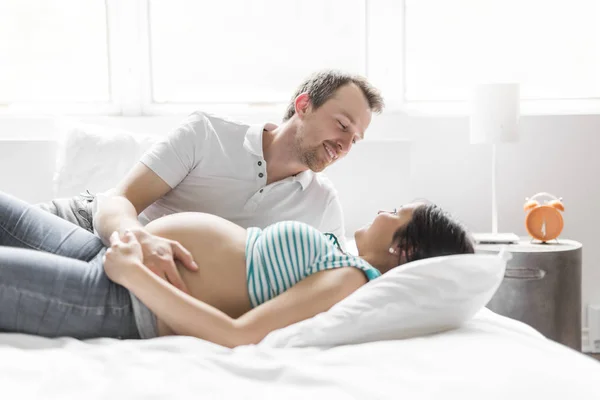 Jeunes parents au lit attendant un petit bébé, Moments romantiques pour couple enceinte — Photo