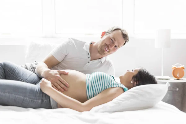 Jovens pais na cama esperando um bebê pequeno, momentos românticos para casal grávida — Fotografia de Stock