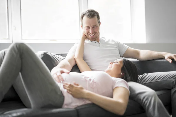 Couple avec femme enceinte se détendre sur le canapé ensemble — Photo
