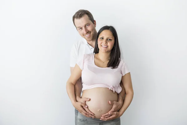 Glad gravid kvinna med make i studio på grå — Stockfoto