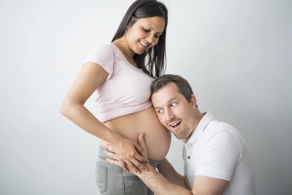 Gelukkig zwangere vrouw met de man in de studio op grijs — Stockfoto