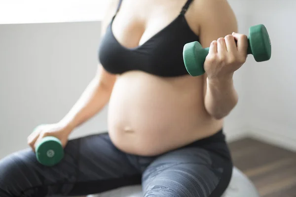 Pregnant woman training with dumbbells to stay active — Stock Photo, Image