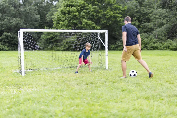 Father with son playing football on football pitch — Stock Photo, Image