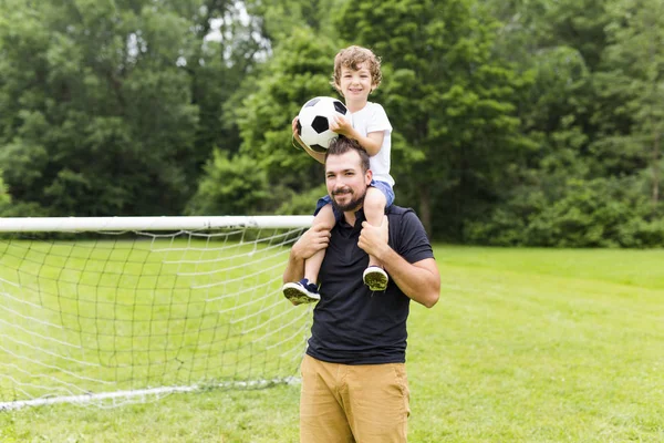 Father with son playing football on football pitch — Stock Photo, Image