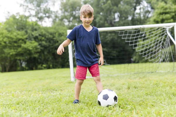 Junge mit Fußball auf dem Feld hat Spaß — Stockfoto