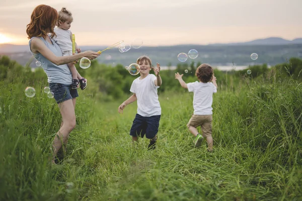 Barn och kvinna Utomhus spelar med såpbubbla på äng — Stockfoto