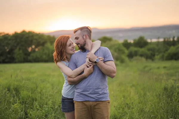 Молодая пара наслаждается закатом на лугу — стоковое фото