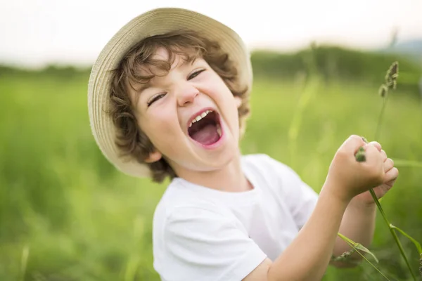 Porträtt av bedårande kid pojke med hatt står på en sommaräng — Stockfoto