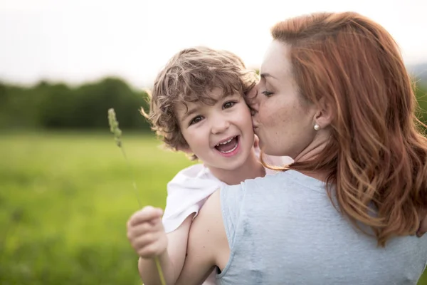 Rapaz bonito com sua mãe em um prado de verão — Fotografia de Stock