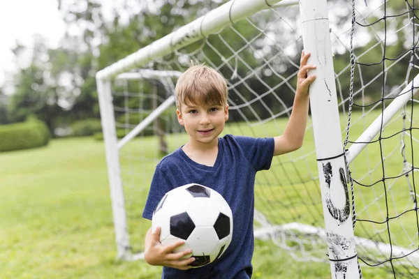 Νεαρό αγόρι με το ποδόσφαιρο σε ένα γήπεδο που έχει τη διασκέδαση — Φωτογραφία Αρχείου