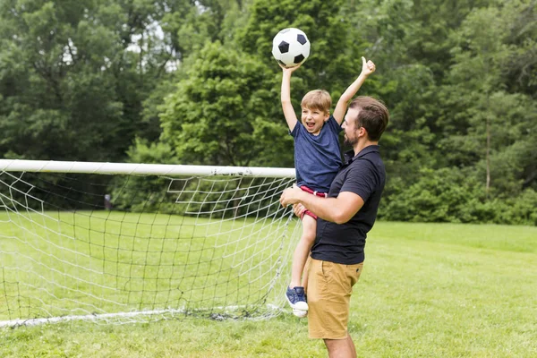 Father with son playing football on football pitch — Stock Photo, Image