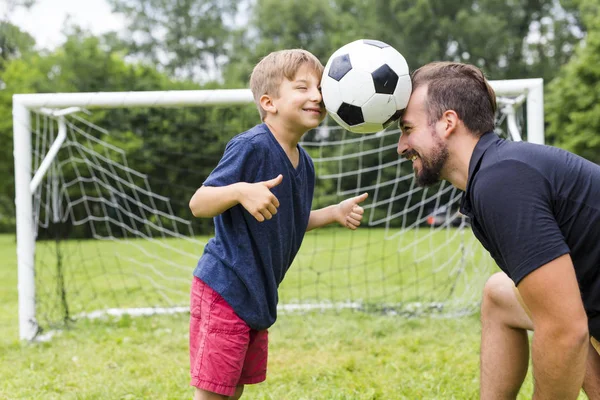 Padre con hijo jugando fútbol en campo de fútbol — Foto de Stock