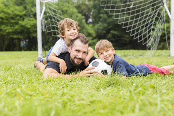 Pai com filho jogando futebol em campo de futebol — Fotografia de Stock