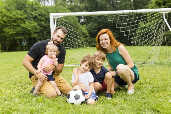 Família feliz com bola de futebol em um campo — Fotografia de Stock